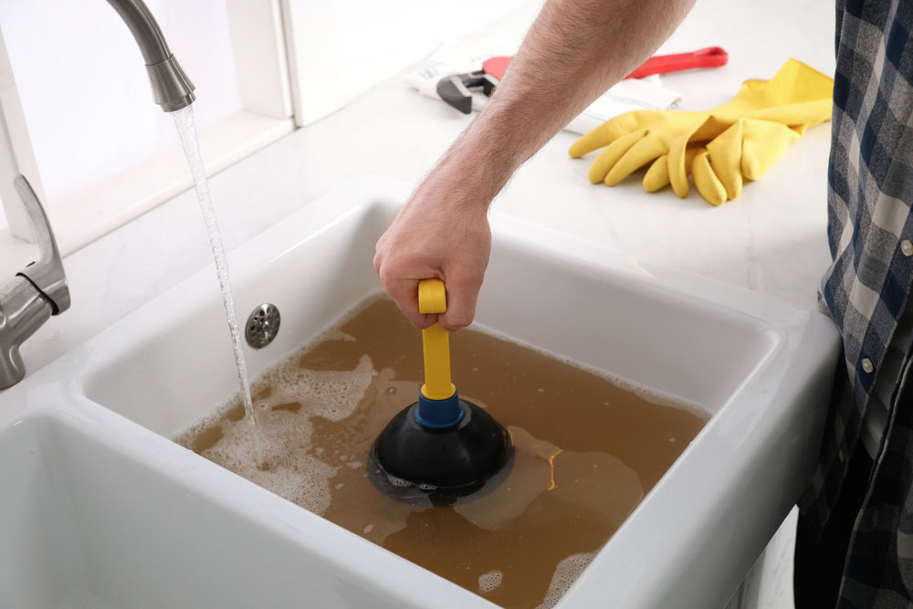 man using plunger to unclog sink drain in kitchen Bellevue, WA man using plunger to unclog sink drain in kitchen Bellevue, WA