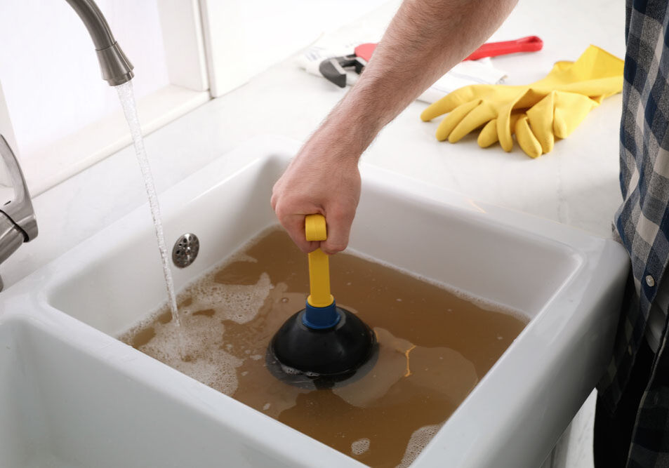 man using plunger to unclog sink drain in kitchen Bellevue, WA